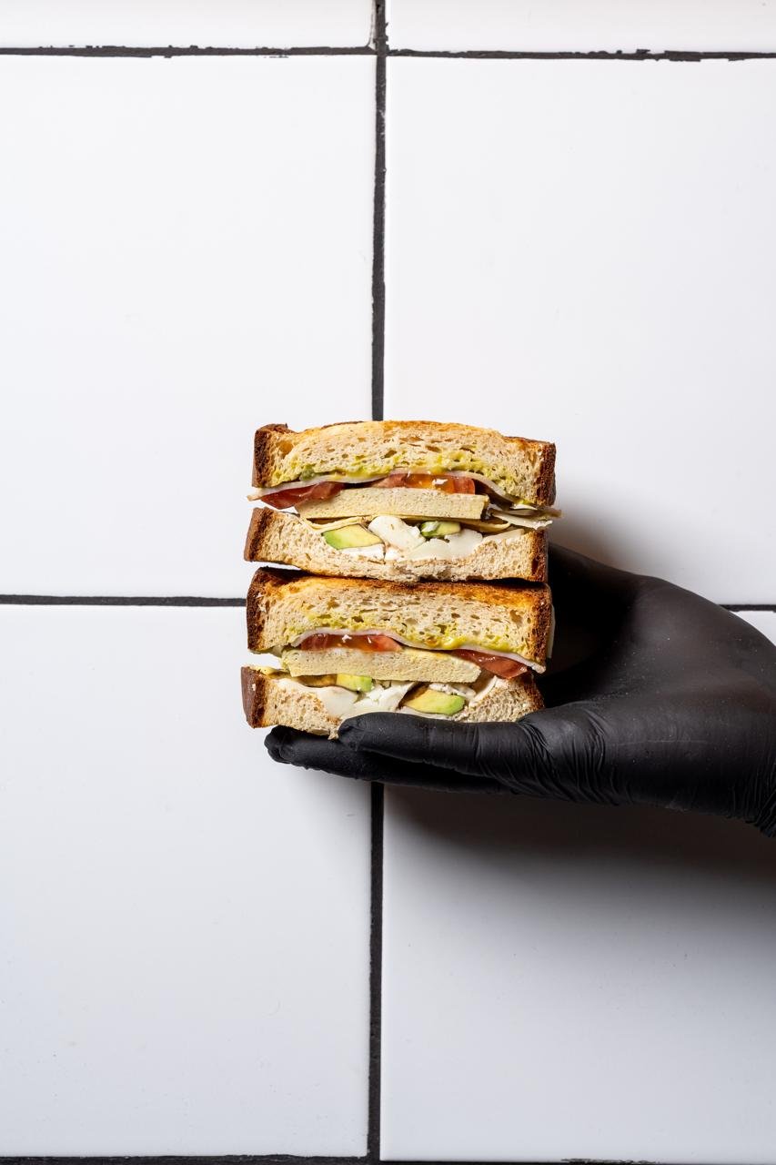 Gluten-free club sandwich held in a gloved hand